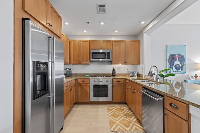 kitchen with visible vents, light wood-style flooring, appliances with stainless steel finishes, stone countertops, and a sink