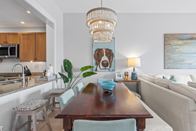 dining space with a notable chandelier, recessed lighting, and light wood-type flooring