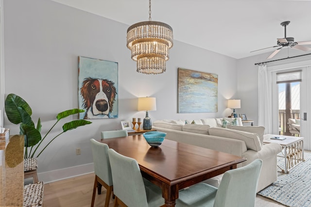 dining area featuring ceiling fan with notable chandelier, light wood-type flooring, and baseboards