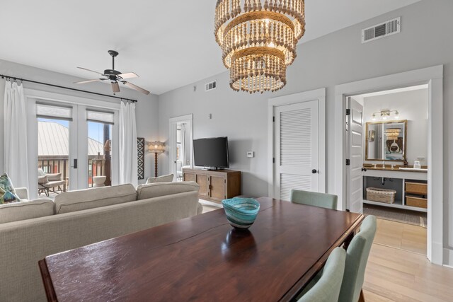 dining space with ceiling fan with notable chandelier and light hardwood / wood-style floors