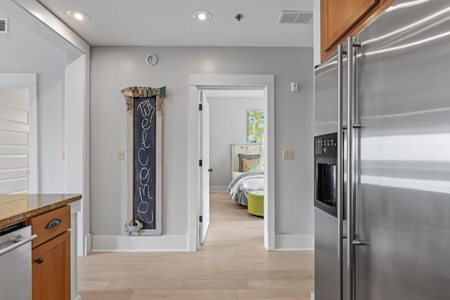 kitchen featuring visible vents, high end fridge, light wood-style floors, and brown cabinets