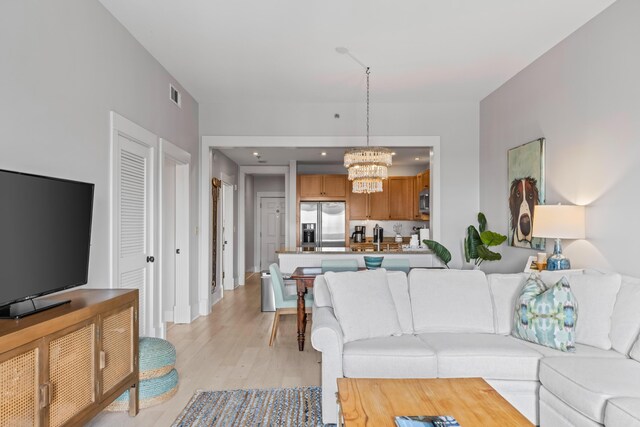 living room with an inviting chandelier and light hardwood / wood-style flooring