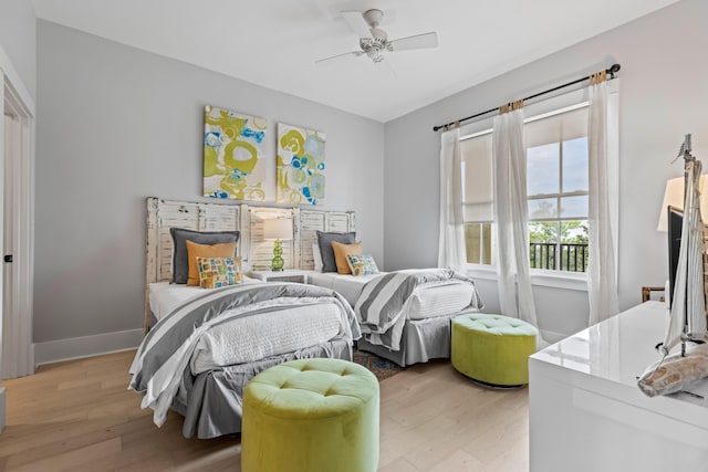 bedroom with light wood-style flooring, a ceiling fan, and baseboards