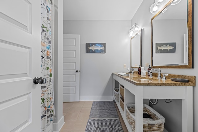 full bathroom with a sink, baseboards, double vanity, and tile patterned flooring