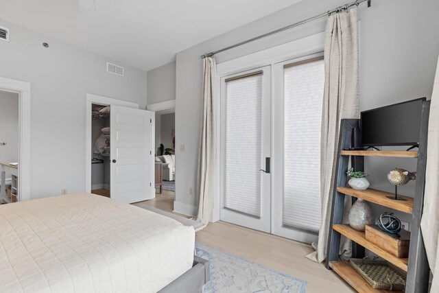 bedroom with french doors, light hardwood / wood-style flooring, a spacious closet, and a closet