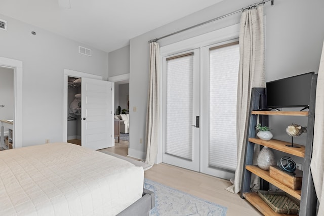 bedroom with visible vents, light wood-style floors, a spacious closet, and access to outside