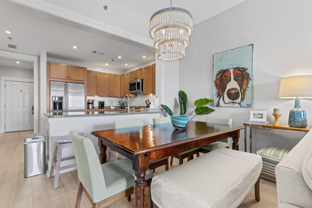 dining space with sink, a chandelier, and light hardwood / wood-style flooring