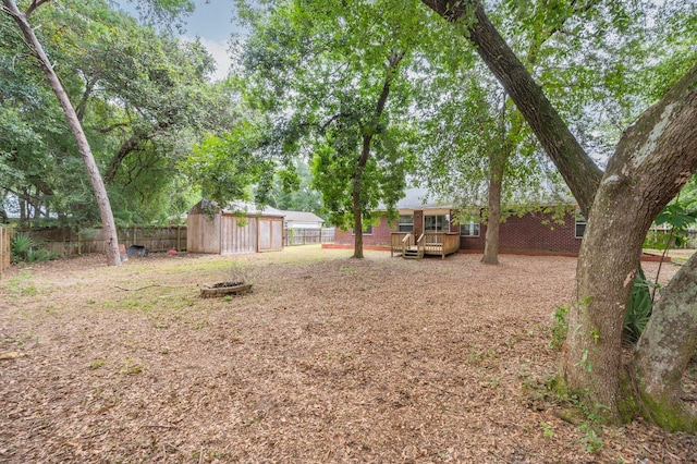 view of yard with a shed, a fire pit, and a deck