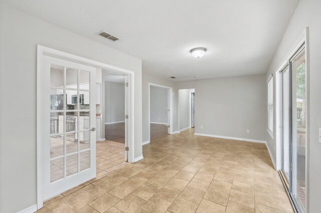 tiled spare room featuring french doors and a textured ceiling