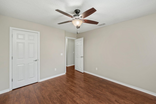 unfurnished bedroom featuring dark wood-type flooring, a textured ceiling, and ceiling fan