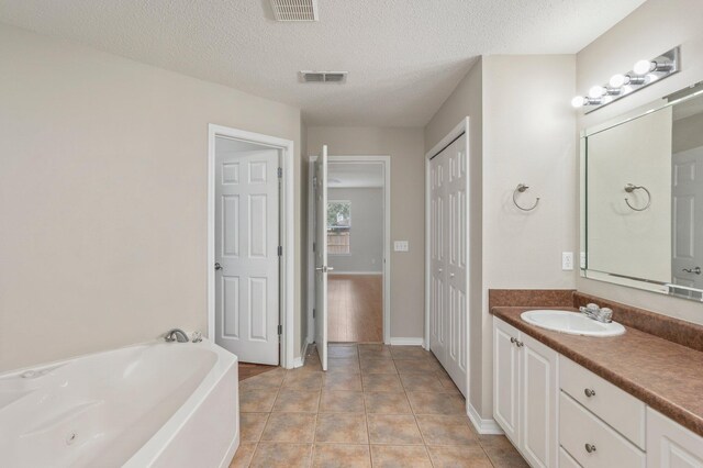 bathroom featuring vanity, a textured ceiling, a tub, and tile patterned flooring