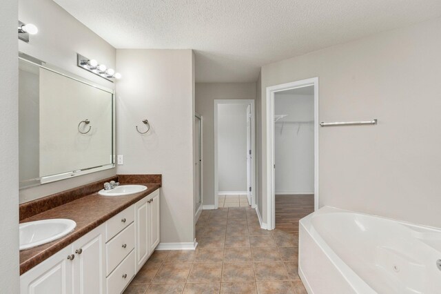 bathroom with tile patterned floors, separate shower and tub, a textured ceiling, and vanity