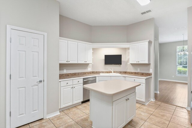 kitchen featuring stainless steel dishwasher, sink, light wood-type flooring, and white cabinetry