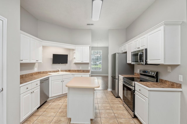 kitchen with white cabinets, a center island, light tile patterned floors, and stainless steel appliances