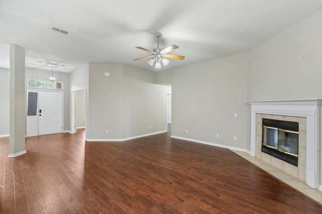 unfurnished living room with a tiled fireplace, wood-type flooring, and ceiling fan