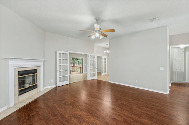 unfurnished living room featuring a textured ceiling, a fireplace, french doors, light hardwood / wood-style floors, and ceiling fan