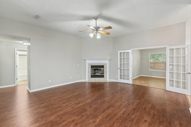 unfurnished living room with a textured ceiling, hardwood / wood-style flooring, ceiling fan, and a tile fireplace