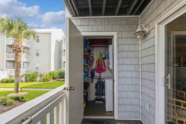 view of exterior entry featuring a yard and a balcony