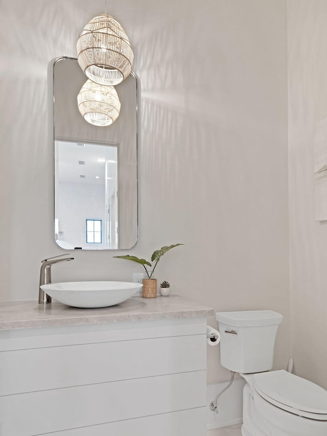 bathroom featuring a chandelier, vanity, and toilet