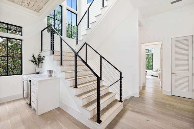 stairs featuring a towering ceiling and wood-type flooring