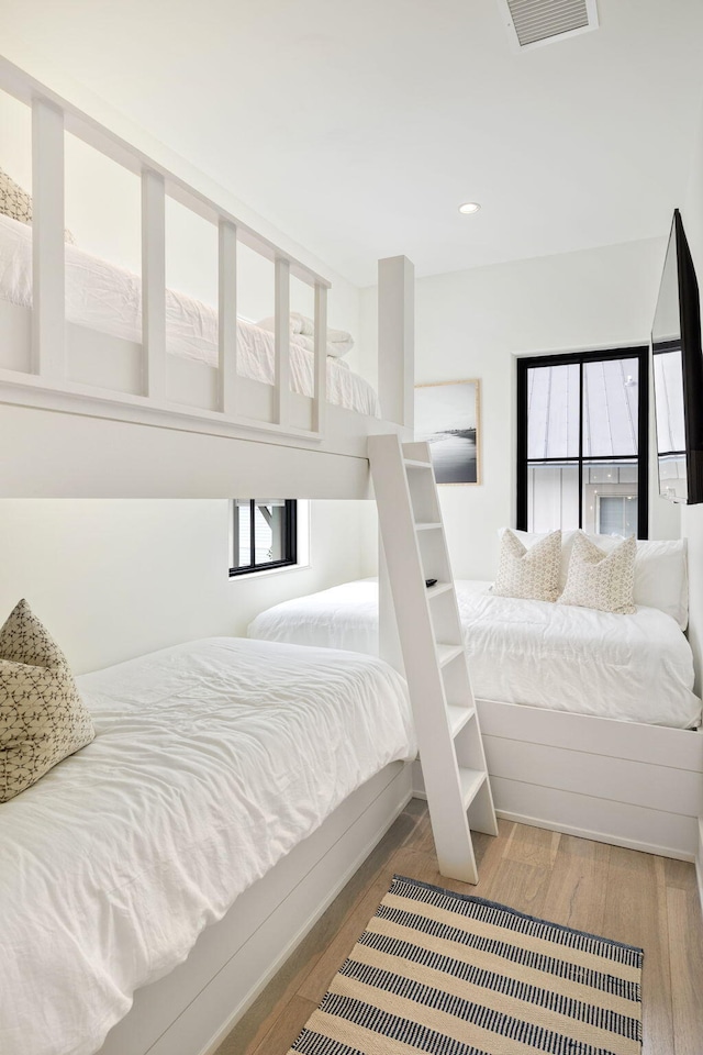 bedroom with hardwood / wood-style floors and multiple windows