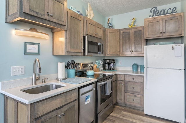 kitchen featuring hardwood / wood-style floors, appliances with stainless steel finishes, a textured ceiling, and sink