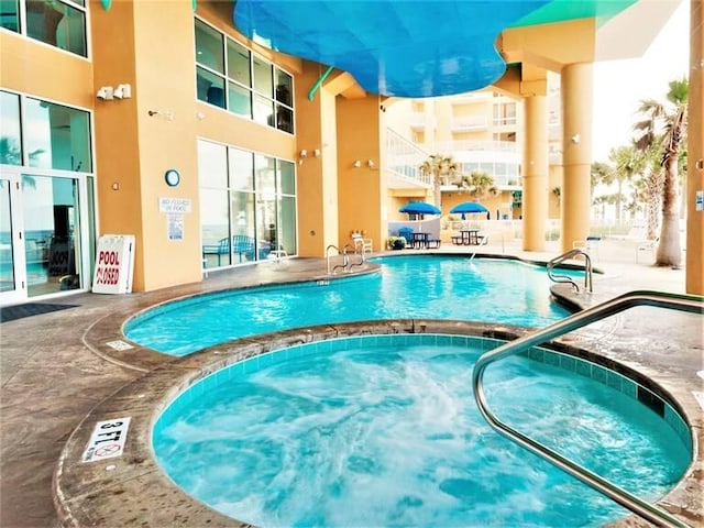 view of swimming pool featuring a hot tub and a patio area