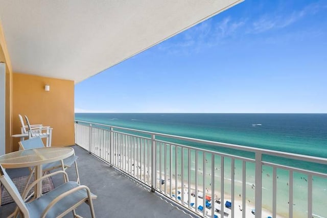 balcony with a water view and a view of the beach