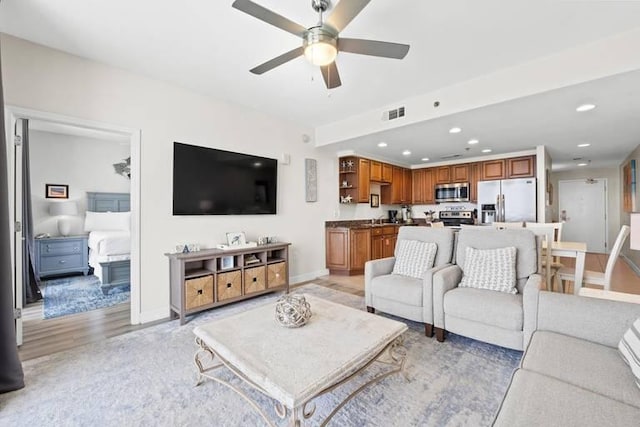 living room featuring light hardwood / wood-style floors, sink, and ceiling fan