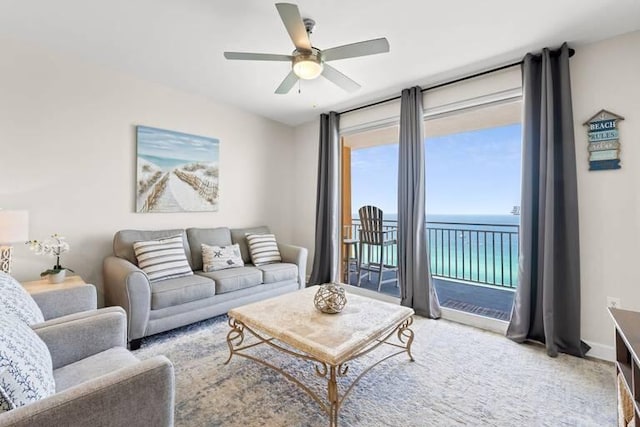 carpeted living room with a water view and ceiling fan