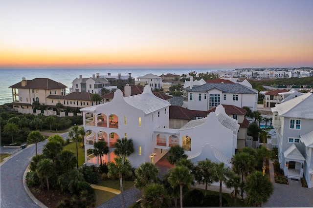 aerial view at dusk featuring a residential view and a water view