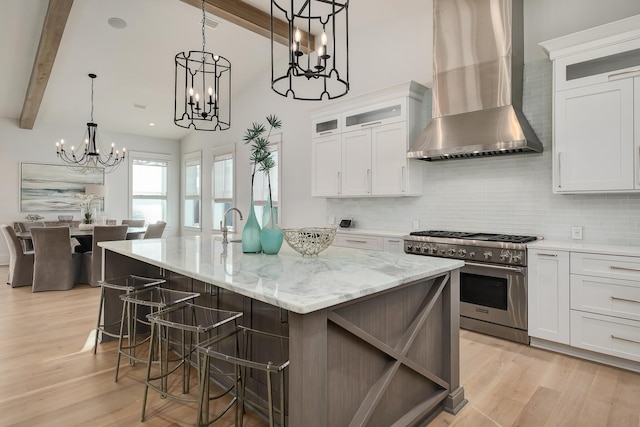 kitchen featuring high end stainless steel range oven, beam ceiling, wall chimney exhaust hood, and backsplash