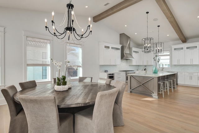 dining area featuring a chandelier, light hardwood / wood-style floors, beamed ceiling, sink, and high vaulted ceiling