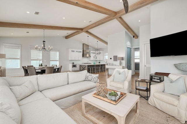 living room with a notable chandelier, lofted ceiling with beams, plenty of natural light, and light wood finished floors