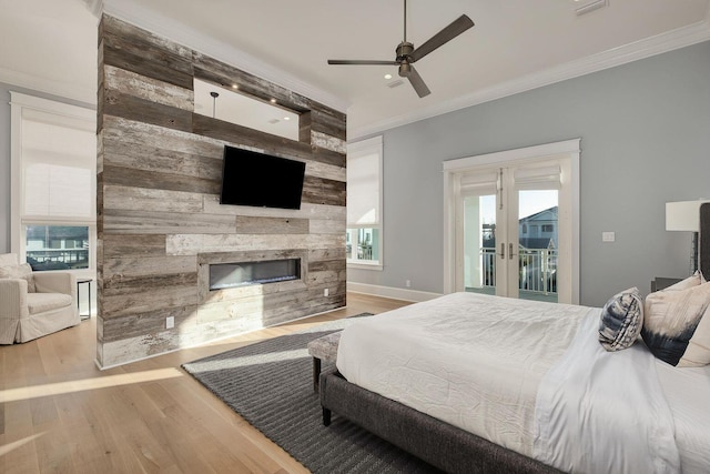 bedroom with access to outside, ornamental molding, wood finished floors, and a large fireplace