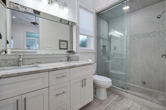 bathroom with a sink, toilet, a stall shower, and double vanity