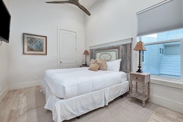 bedroom featuring a ceiling fan, lofted ceiling, baseboards, and wood finished floors