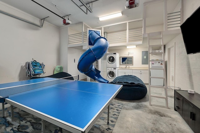 playroom featuring stacked washer and clothes dryer, electric panel, a sink, unfinished concrete flooring, and a garage