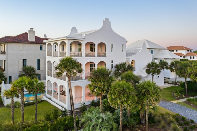 mediterranean / spanish house featuring a balcony, a swimming pool, and a yard