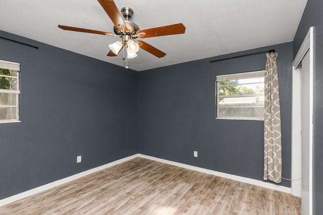 spare room featuring a healthy amount of sunlight, ceiling fan, and light hardwood / wood-style flooring