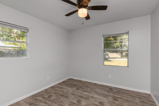 empty room featuring dark wood-type flooring, a wealth of natural light, and ceiling fan