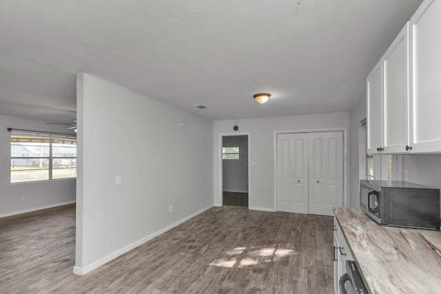 interior space with light stone countertops, ceiling fan, hardwood / wood-style floors, stainless steel appliances, and white cabinets