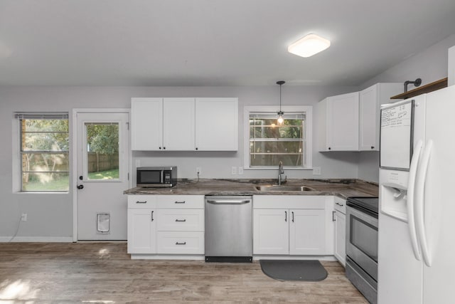 kitchen with stainless steel appliances, hanging light fixtures, light hardwood / wood-style floors, and white cabinetry