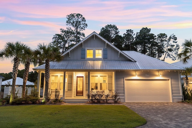 view of front of house with a garage, a porch, and a lawn