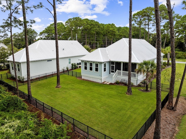 rear view of property featuring a yard, metal roof, and fence private yard