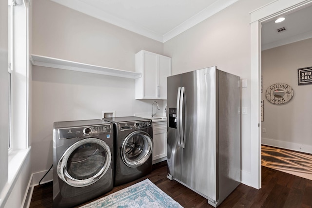 laundry room featuring cabinets, crown molding, washing machine and clothes dryer, and dark hardwood / wood-style flooring