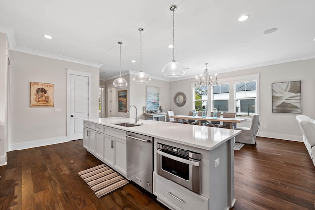 kitchen with appliances with stainless steel finishes, pendant lighting, white cabinetry, sink, and a center island with sink