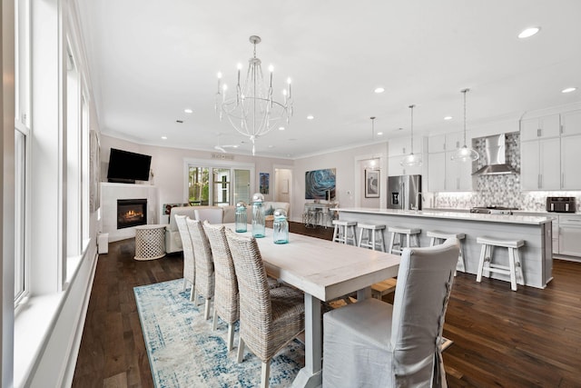 dining space with a glass covered fireplace, crown molding, recessed lighting, and dark wood-style flooring