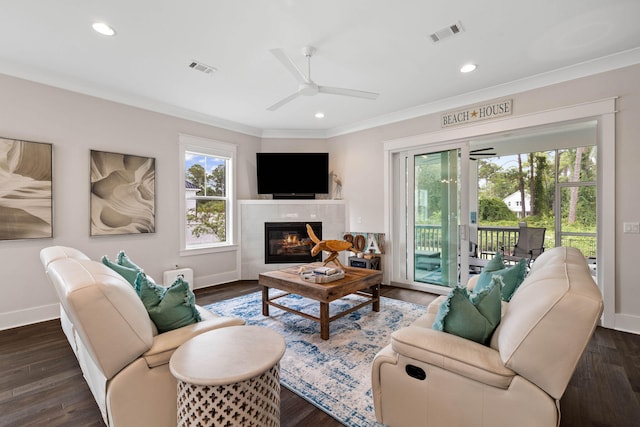 living room with dark wood-type flooring, a fireplace, ornamental molding, and ceiling fan