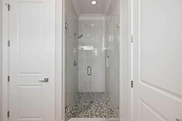 bathroom featuring ornamental molding and a shower with shower door